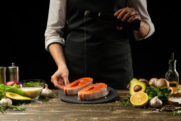 厨师准备新鲜的鲑鱼，鳟鱼，橄榄油和蔬菜水。水平的照片。概念烹饪健康素食菜肴，清洁食品，餐饮，酒店业务图片下载