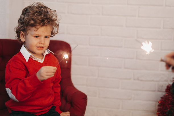 妈妈和太阳坐在地板上，在圣诞装饰的演播室里燃放烟花图片下载