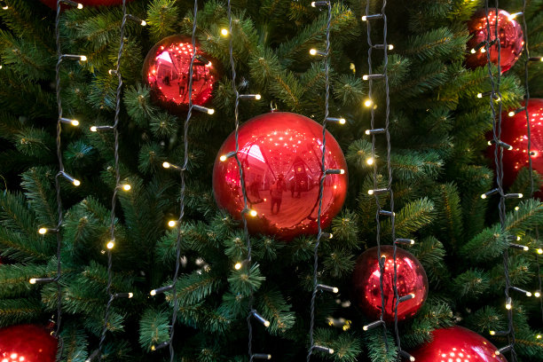 装饰圣诞树特写。红色和金色的球和手电筒照亮的花环。新年装饰物微距照片与散景。寒假灯饰图片下载