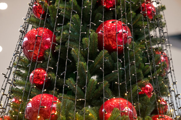 装饰圣诞树特写。红色和金色的球和手电筒照亮的花环。新年装饰物微距照片与散景。寒假灯饰图片下载