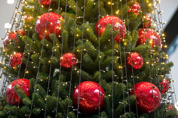 装饰圣诞树特写。红色和金色的球和手电筒照亮的花环。新年装饰物微距照片与散景。寒假灯饰图片下载