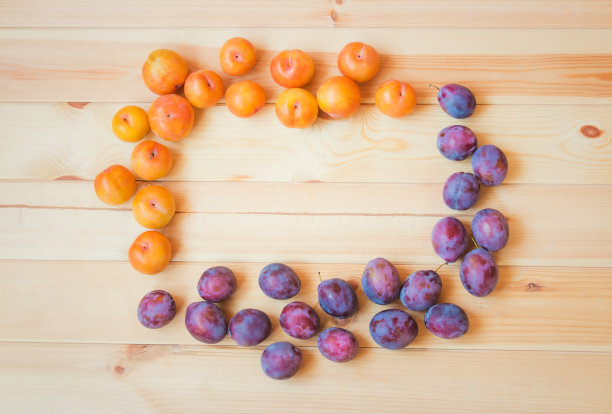 框架由新鲜的彩色梅子木制背景。图片下载