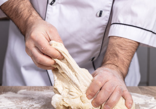 男厨师在桌上揉面团图片下载