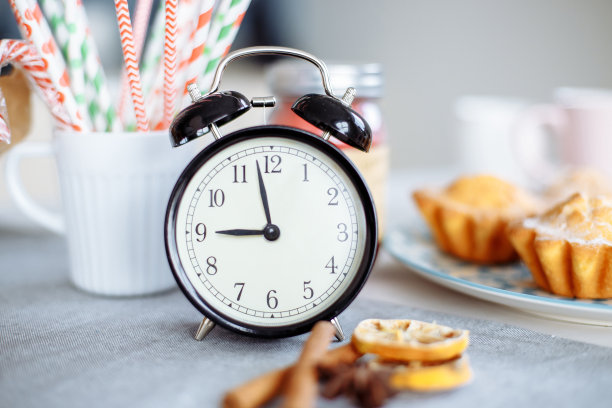 灰色的桌子上放着闹钟和早餐。图片下载