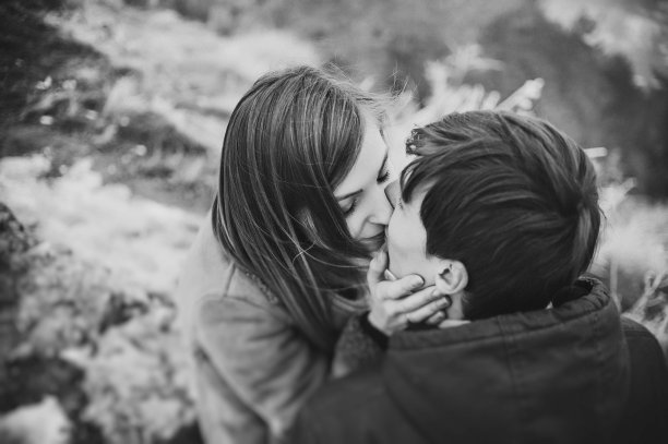 一对浪漫的情侣在雪地公园散步。寒假。男人和女人拥抱亲吻，享受散步。黑白照片。图片下载