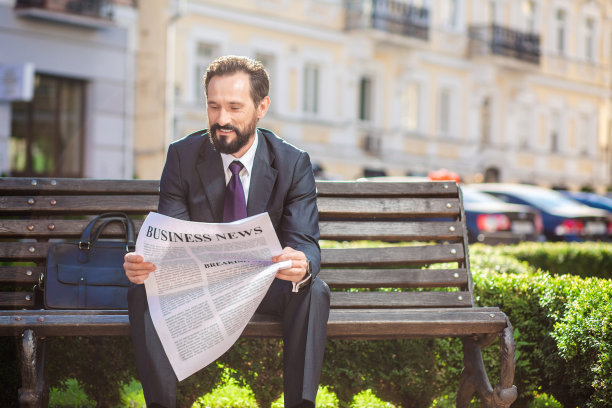 愉快微笑的商人在读商业报纸图片下载