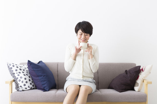 一个女人坐在沙发上，享受着一杯饮料图片下载