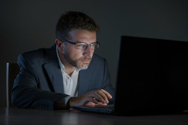 年轻貌美、敬业的企业家，工作到深夜，用笔记本电脑在外汇市场或金融业务上进行交易，在黑暗的背景下分析数据图片下载