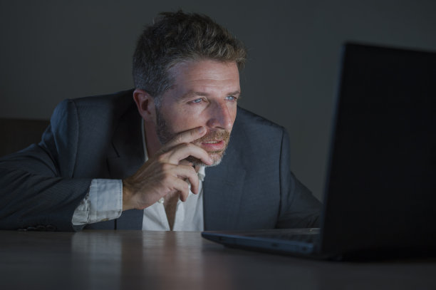 年轻貌美、敬业的企业家，工作到深夜，用笔记本电脑在外汇市场或金融业务上进行交易，在黑暗的背景下分析数据图片下载