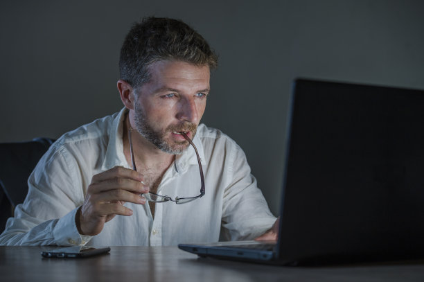 年轻貌美、疲惫的戴着眼镜的工作狂企业家，使用笔记本电脑在外汇市场或金融业务上进行交易，在黑暗的背景下分析数据图片下载