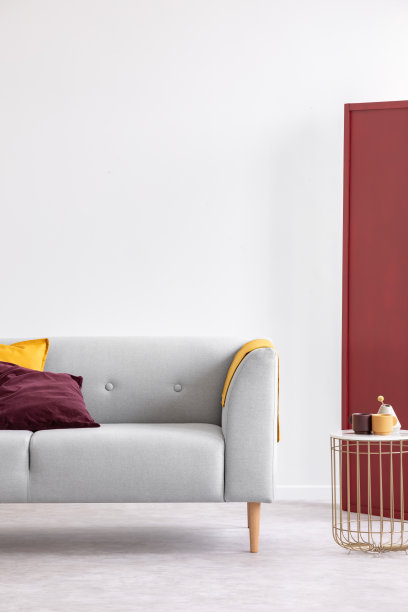 垂直视图时尚的金色咖啡桌和两个咖啡杯和小花瓶旁边优雅的沙发枕头，真实的照片与复制空间在空白的白色墙壁图片下载