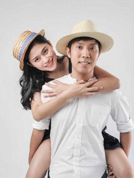 快乐的亚洲夫妇戴着帽子和骑在白色的背景。图片下载