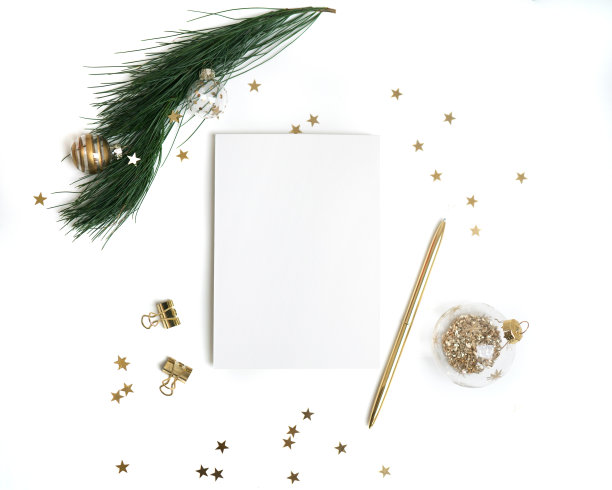 圣诞贺卡模板在黄金。空纸模型，冷杉树枝与玻璃球装饰，星星五彩纸屑，笔在白色背景。图片下载