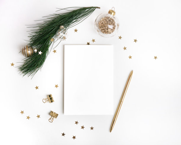 圣诞贺卡模板在黄金。空纸模型，冷杉树枝与玻璃球装饰，星星五彩纸屑，笔在白色背景。图片下载