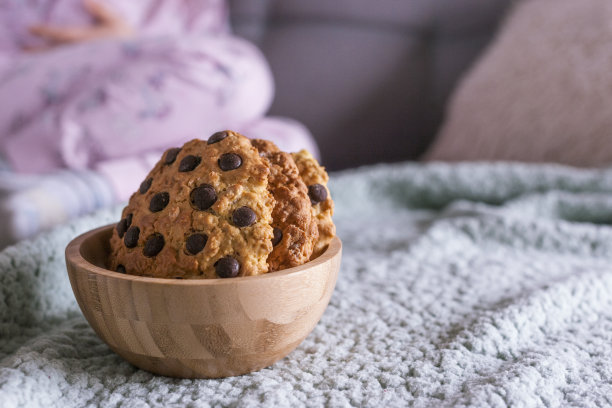 家庭烘焙和婴儿。小女孩在沙发上吃饼干。用自然光拍摄复古照片。文本的空闲空间。图片下载