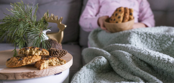 那女孩吃了一顿美味的巧克力饼干早餐。一个孩子坐在圣诞树的树枝上。照片中的家的舒适和自然光线。文本的空闲空间。图片下载