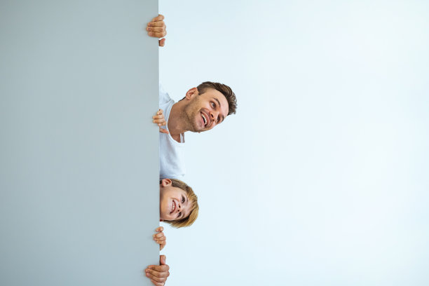 快乐的父亲和儿子站在墙后图片下载