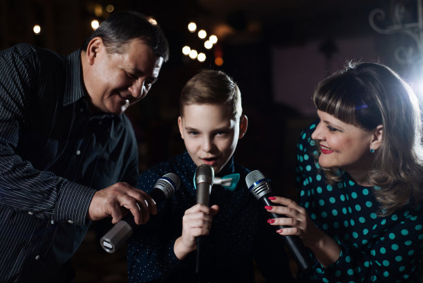 家庭卡拉ok。一个幸福的家庭，在麦克风里唱歌图片下载