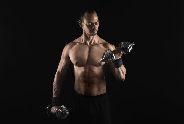 强壮的运动员举着哑铃，露出赤裸的肌肉图片下载