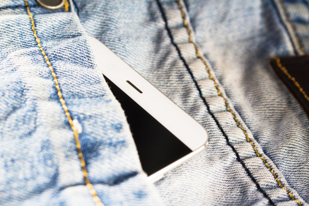 蓝色牛仔裤里藏着白色智能手机图片下载