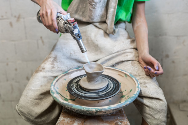 裁剪近距离的照片自信的手工艺术家女士在她的工作服，她坐在工作空间里用喷灯制作陶瓷产品图片下载