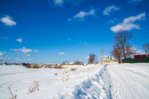 冬天的风景。农村。雪道路。阳光明媚的一天。蓝色的天空。白云。图片下载