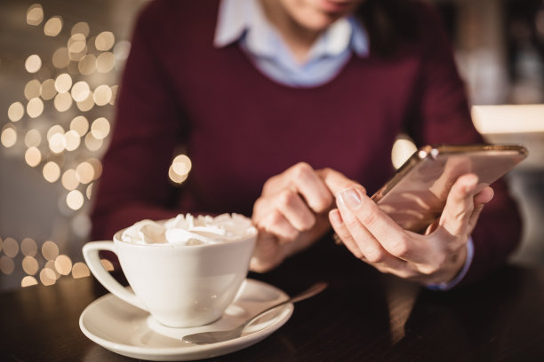 美丽的黑发女人，用手机，在咖啡厅喝咖啡图片下载