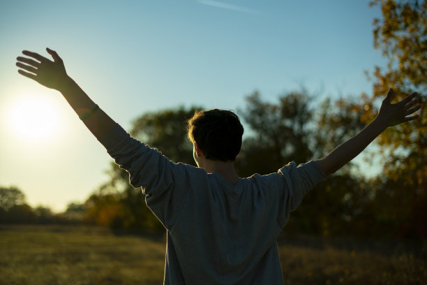 年轻快乐的家伙享受生活举起双手对着天空看日落Ð°图片下载