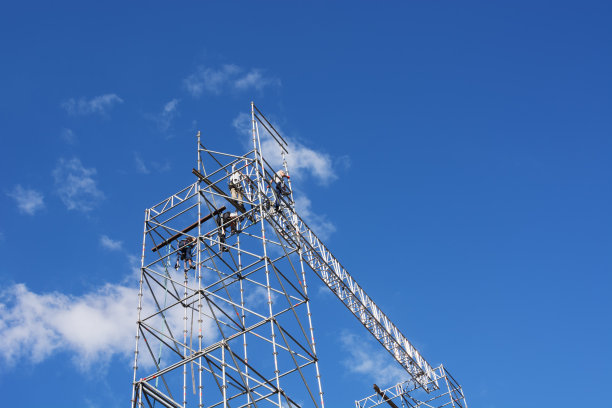 在蓝天下，无法辨认的建筑工人在搭建脚手架图片下载