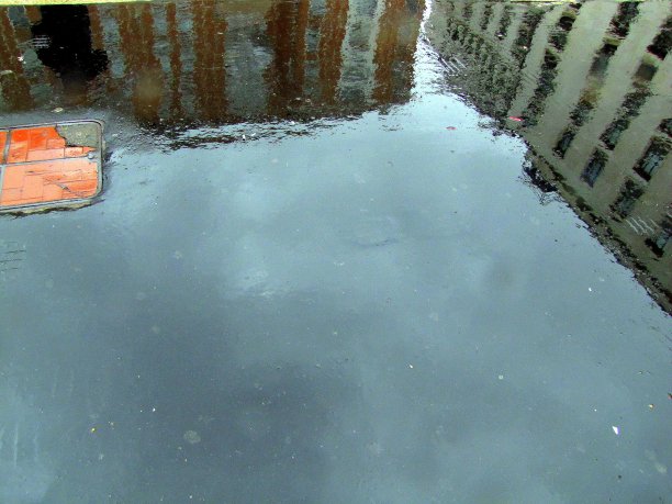 雨水漫过水坑里建筑物的彩色倒影图片下载