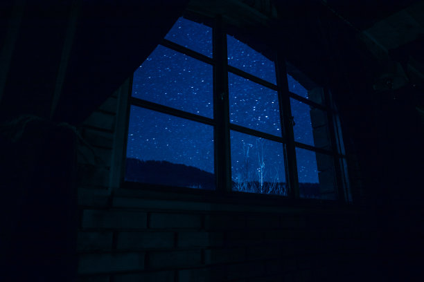 从黑暗的房间里透过窗户看到的星星夜景。暗室里的夜空。图片下载