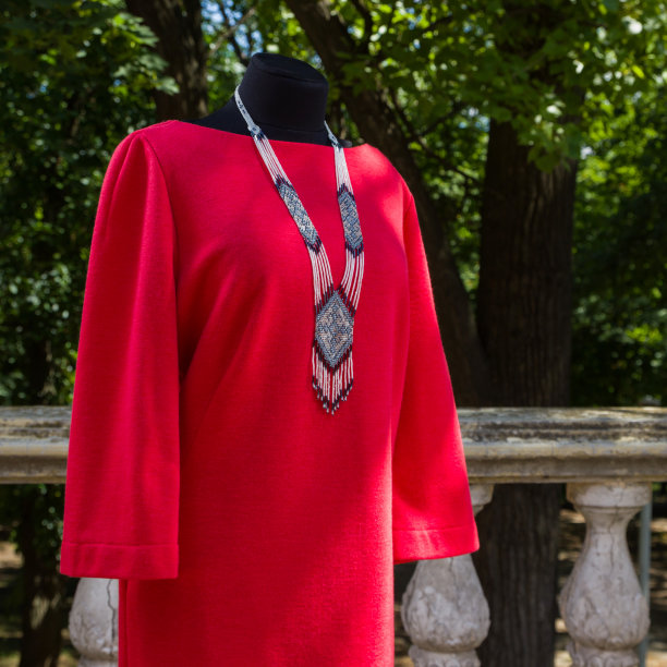 穿着红色衣服的模特。秋日女式长袖连衣裙。女装直剪背景上的石柱。个人定制图片下载