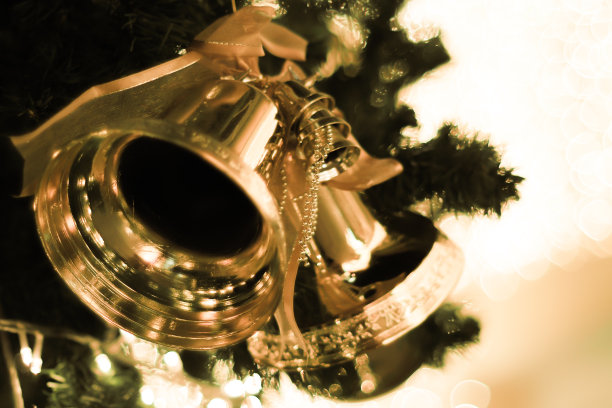 圣诞树上的金色铃铛和红色蝴蝶结模糊了明亮的散景背景图片下载