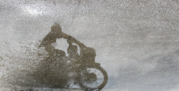 骑手和摩托车在潮湿的路面上的影子。图片下载