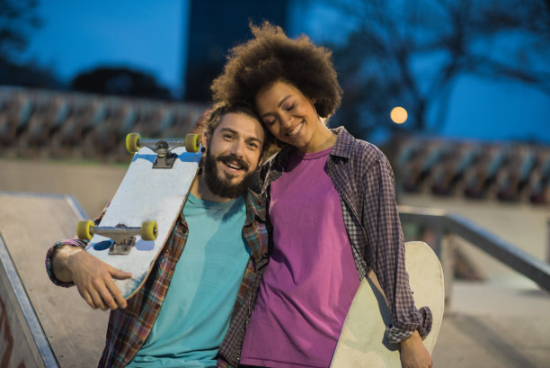 幸福的女人闭着眼睛拥抱着一个玩滑板的男人图片下载