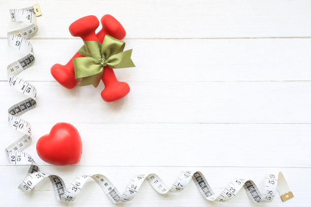 俯视图绿色丝带与哑铃和健康心脏的测量带木制白色背景，保健理念图片下载