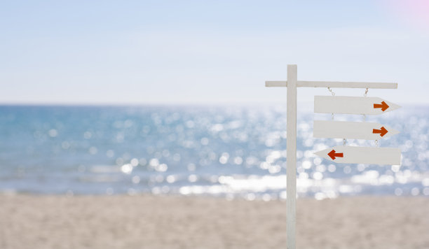 木制箭头招牌在美丽的热带蓝色海与白色的海滩，空白的白色木制招牌在海滩拷贝空间。图片下载