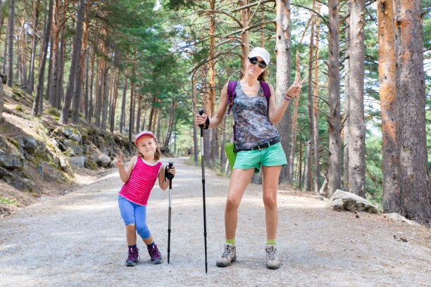 在马德里的森林里，一个女人和一个小女孩手拿胜利的标志摆姿势图片下载