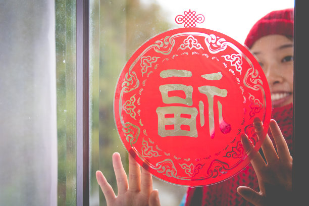 春节期间在窗户上贴红纸的女人素材图片
