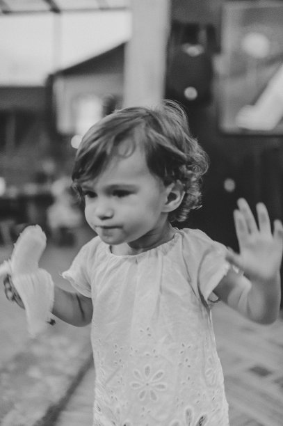 小女孩宝宝站在夏夜小镇的街边餐馆里吃香蕉的照片。家庭度假和假期的概念。黑白照片。图片下载