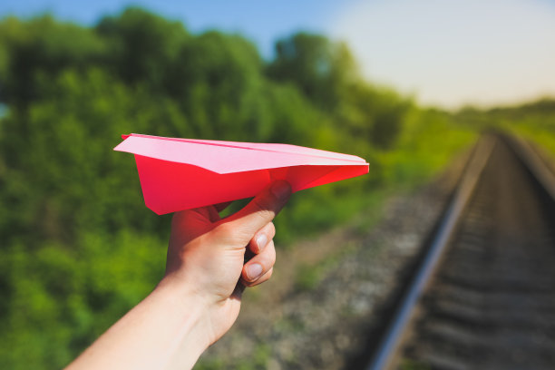 那家伙拿着一架粉红色的手工飞机。自由概念照片与轨道在绿色领域。铁路运输行业。夏日空旷的道路。旅行的生活动力。图片下载