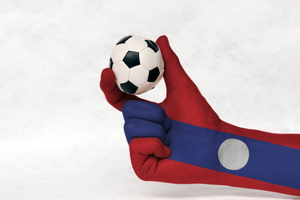 老挝国旗彩绘手握迷你足球，用两根手指将其放在白色背景上。图片下载