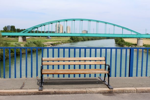 公共木凳，熟铁腿和旧的金属拱形铁路桥为背景图片下载