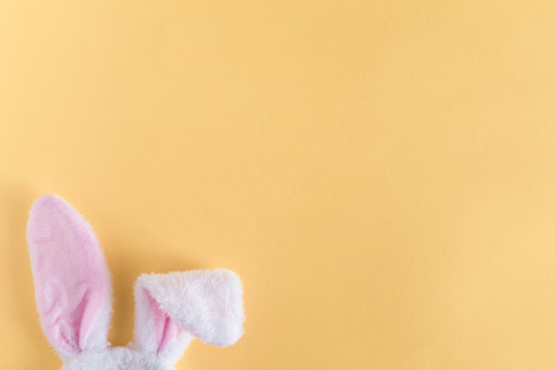 装饰和符号俯视图。复活节快乐节日背景概念。平放配件兔子耳朵在黄色的桌子上。为设计或文本提供自由空间。图片下载