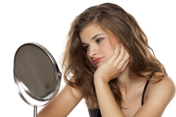 年轻而乐观的女人在白色背景下照镜子图片下载