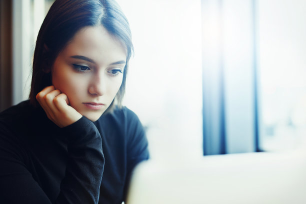 女人在咖啡馆用笔记本电脑工作时环顾四周并微笑。一个穿着冬装在笔记本电脑前工作的时尚微笑女人的肖像。女性与太阳的商务风格。——图片图片下载