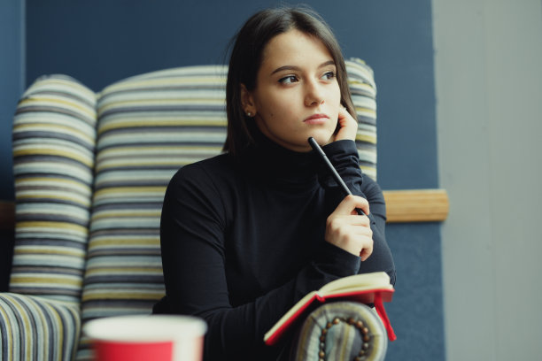 女人做笔记并四处寻找想法。冬天穿着衣服的时尚微笑女人的肖像女性冬季风格。——图片图片下载