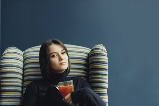 女人戴眼镜，在咖啡馆用笔记本电脑工作时喝热茶。这是一个穿着冬装、喝着热茶、在笔记本电脑前工作的时尚微笑女人的肖像。女性冬季风格。——图片图片下载