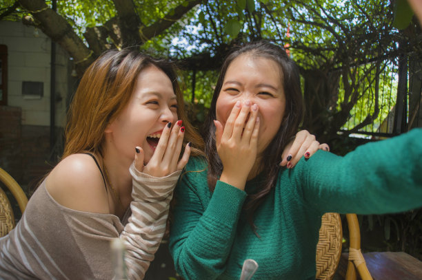两个年轻快乐和可爱的亚洲中国女友用手机相机自拍照片在网络社交媒体上使用，同时在咖啡厅吃健康的早午餐的生活方式肖像图片下载
