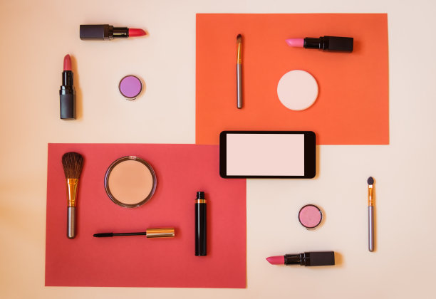 彩妆化妆品，智能手机和画笔彩色纸背景。图片下载